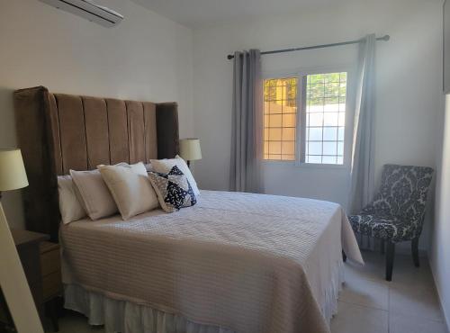 1 dormitorio con cama, ventana y silla en Linda, cerca de todo, parqueo, patio, netflix en La Ceiba