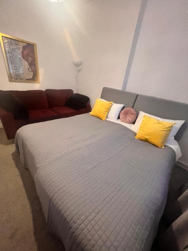 1 dormitorio con cama con almohadas amarillas y sofá en Spacious Double Room in prime location London, en Londres