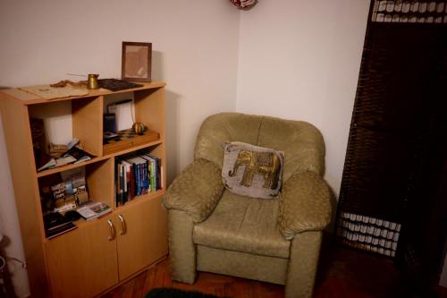 a living room with a chair and a book shelf at E-19 Home - Tradition meets tourism in Prizren