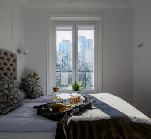 ein Tablett mit Essen auf einem Bett mit Fenster in der Unterkunft Warsaw Seasons by Alluxe Boutique Apartments in Warschau