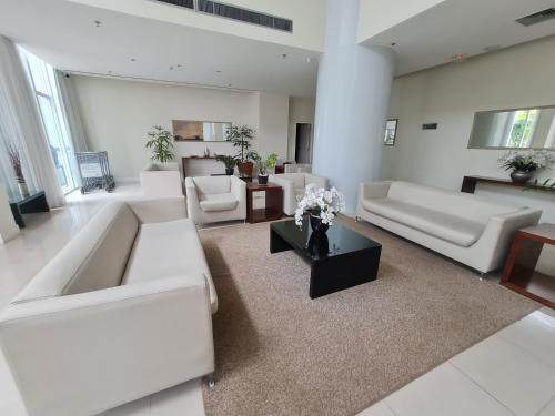 a living room with white couches and a table at BSB FLAT - MELHOR LOCALIZAÇÃO in Brasilia