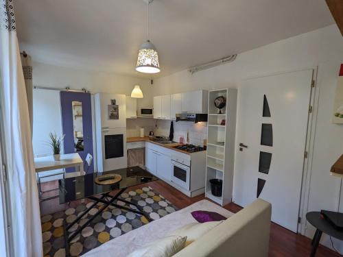 eine Küche mit weißen Schränken und einem Sofa in einem Zimmer in der Unterkunft Appartement - City center in Montpellier