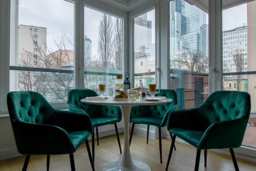 a table with green chairs in a room with windows at Warsaw Seasons by Alluxe Boutique Apartments in Warsaw