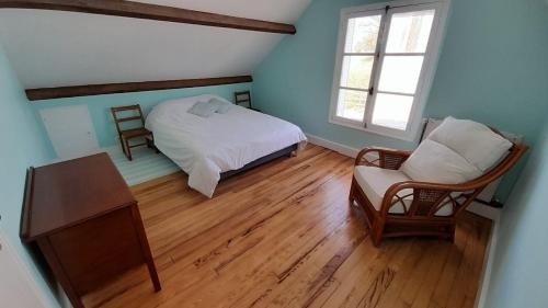 a bedroom with a bed and a chair and a window at Gîte Cottage chaleureux en pleine campagne vue sur les Monts et Forêts et le château de Carrouges in Carrouges