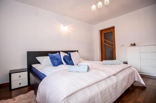 1 dormitorio con 1 cama grande con almohadas azules en Apartamenty Przystanek Bańska, en Bańska Niżna