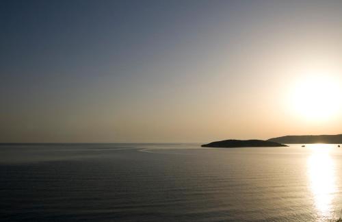 una puesta de sol sobre el agua con una pequeña isla en Kera Studios, en Kalyves