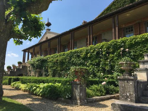 un edificio con un seto y flores delante de él en Clos de Mont July, chambres avec vue et terrasse dans demeure historique, en Ceyzériat