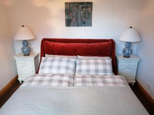 a bed with a red headboard and two night stands at Sunnyside House in Gardenstown