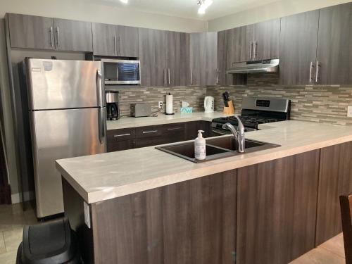 a kitchen with a sink and a stainless steel refrigerator at Signature Suites By Oasis Corporate Rentals in Grande Prairie