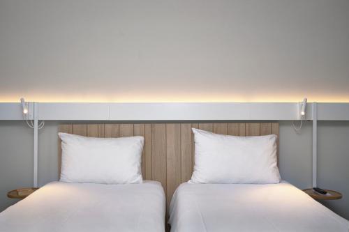 two white beds with pillows and pillows on them at Ibis Annecy - Cran-Gevrier in Annecy
