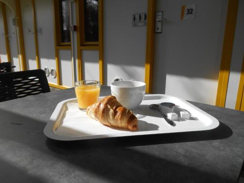 a plate with a cup of orange juice and a croissant at Premiere Classe Brest Gouesnou Aeroport in Gouesnou