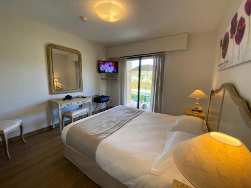 a bedroom with a bed and a desk and a mirror at Hôtel Le Colombier in Moustiers-Sainte-Marie