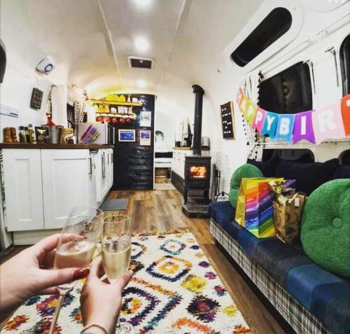 a group of people holding drinks in a rv living room at Airstream Woodland Escape in Galston