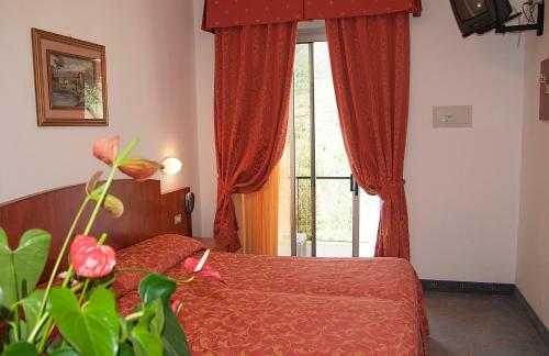 リモーネ・スル・ガルダにあるHotel Gardenのベッドルーム1室(ベッド1台付)、赤いカーテン付きの窓が備わります。