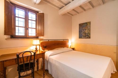 a bedroom with a bed and a desk with a lamp at Podere San Selvatico in Città della Pieve