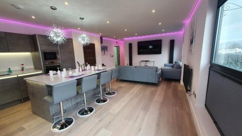 a kitchen and living room with a bar with purple lighting at Central Penthouse with Hot Tub & Views 24 Cheltenham in Cheltenham
