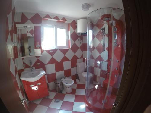 a red and white bathroom with a shower and a toilet at Guest House del Mare in Dobra Voda