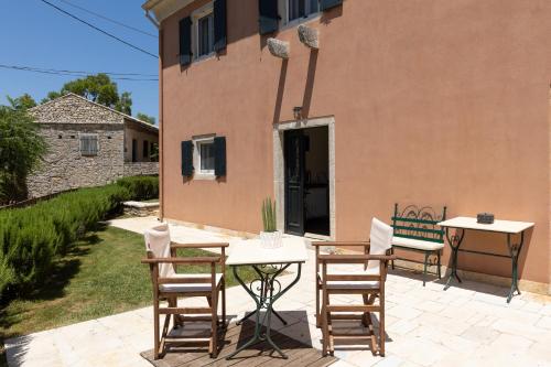 a patio with two tables and chairs and a building at The Merchants House in Perítheia