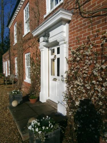 uma porta branca da frente de uma casa de tijolos em The Dower House em Fakenham