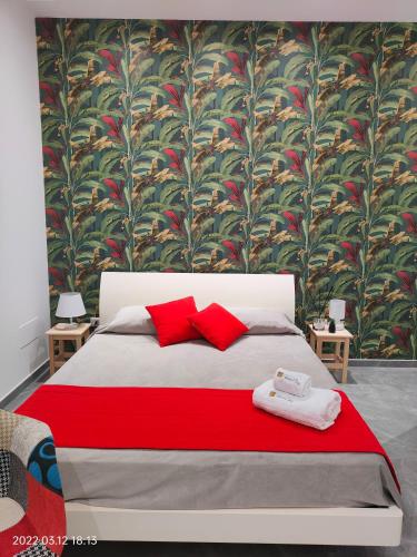 a bedroom with a bed with red pillows and a wallpaper at Bed Nonnonino in Porto Cesareo