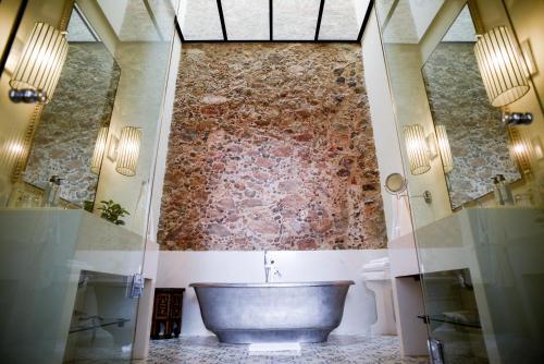 a bathroom with a large tub and a wall at Hotel Casa Blanca 7 in San Miguel de Allende