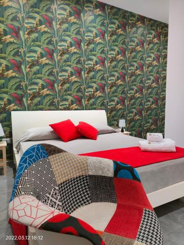 a bedroom with a bed with red pillows and a wallpaper at Bed Nonnonino in Porto Cesareo
