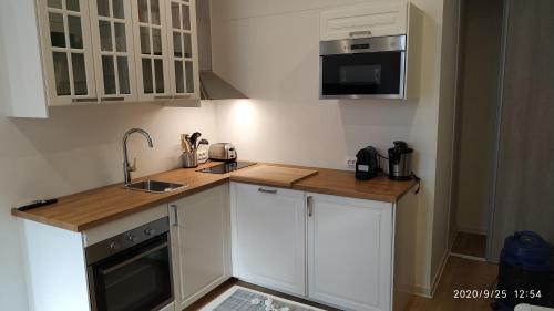 une cuisine avec des armoires blanches et un comptoir en bois dans l'établissement Studio Neuf climatisé tout équipé #2, à Toulon