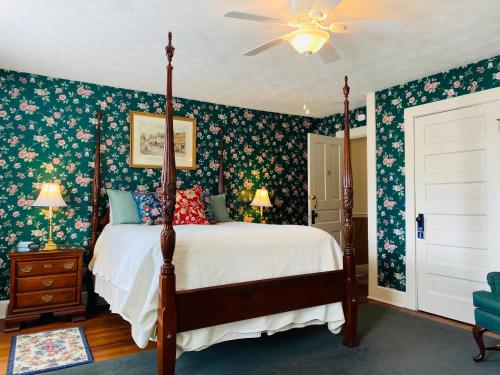 1 dormitorio con cama con dosel y papel pintado con motivos florales en Terrell House B&B en Burnsville