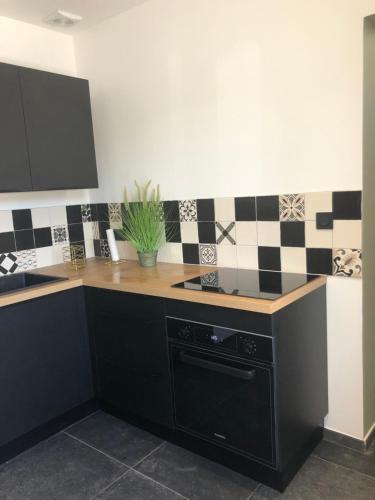 - une cuisine avec du carrelage noir et blanc sur le mur dans l'établissement Charmante maison aux portes des Cévennes, à Alès