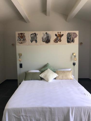 a bedroom with a large white bed with pictures on the wall at Charmante maison aux portes des Cévennes in Alès