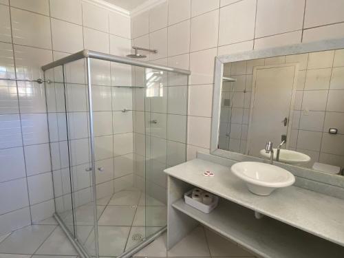 uma casa de banho com um chuveiro, um lavatório e um espelho. em Kalug - Guest House com 3 quartos em Condomínio na Praia dos Milionários em Ilhéus