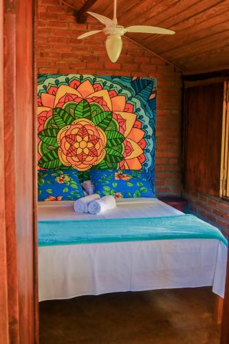 a bed in a room with a painting on the wall at Pousada Guaiamum in Itacaré