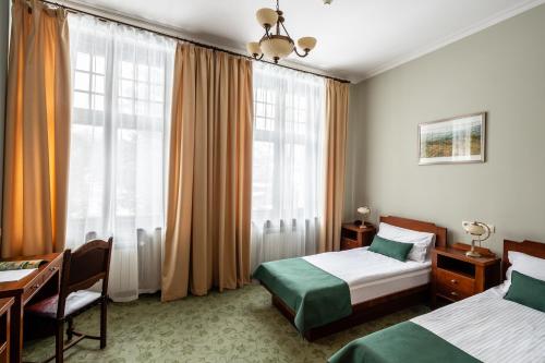 a hotel room with two beds and a desk at Villa Elise Park Pension in Stronie Śląskie