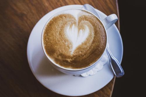 a cup of coffee on a plate with a heart painted on it at Villa Elise Park Pension in Stronie Śląskie