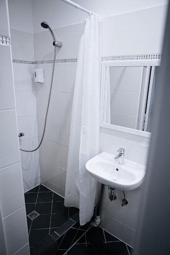 a white bathroom with a sink and a shower at Vallery Guest House in Bigauņciems