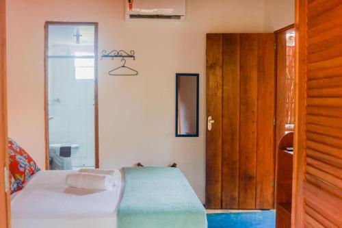 a bedroom with a bed and a wooden door at Pousada Guaiamum in Itacaré