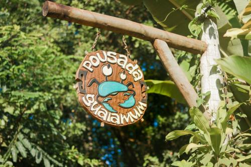 a wooden sign hanging on a tree branch at Pousada Guaiamum in Itacaré