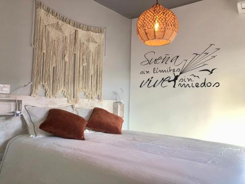 a bedroom with a bed with white sheets and a chandelier at El Rinconcito de Bejar in Béjar