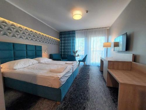 a hotel room with a large bed and a desk at Modern studio in the Caesers Garden resort, Swinoujscie in Świnoujście