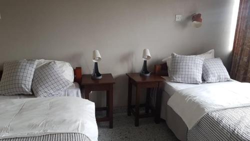 1 dormitorio con 2 camas y 2 mesitas de noche con lámparas en Ibex Hill apartment en Lusaka