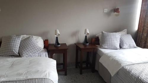 a bedroom with two beds and two night stands with lamps at Ibex Hill apartment in Lusaka
