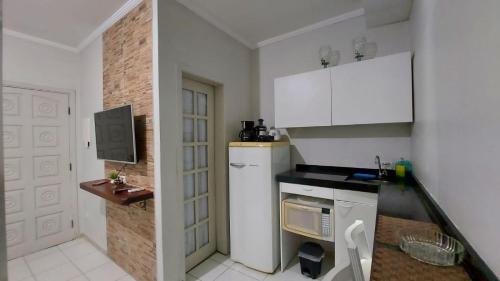 una pequeña cocina con armarios blancos y microondas en KITNET UBA com ar condicionado en Ubatuba