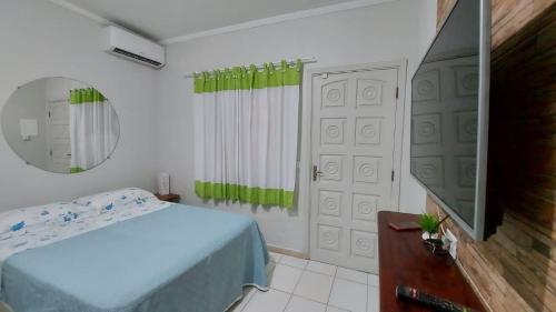 ein Schlafzimmer mit einem Bett und einem Spiegel sowie einem TV in der Unterkunft KITNET UBA com ar condicionado in Ubatuba