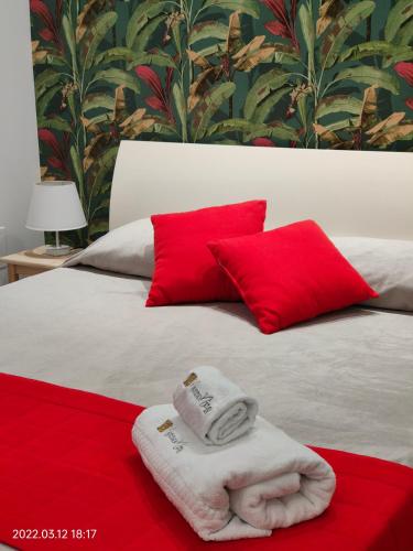 a bed with two red pillows and a towel at Bed Nonnonino in Porto Cesareo