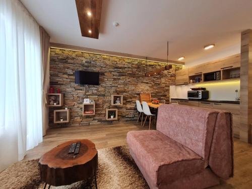 a living room with a couch and a brick wall at Lux Apartman Lucky in Kopaonik