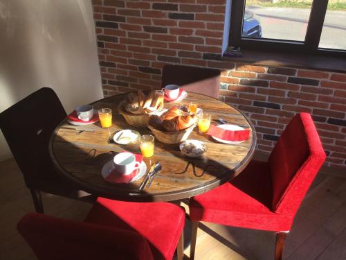 a wooden table with food on it with red chairs at L'Atelier 1 in Corcelles-les-Arts