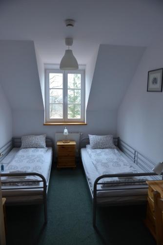 two twin beds in a room with a window at Pokoje Gościnne Domu Pielgrzyma w Supraślu in Supraśl