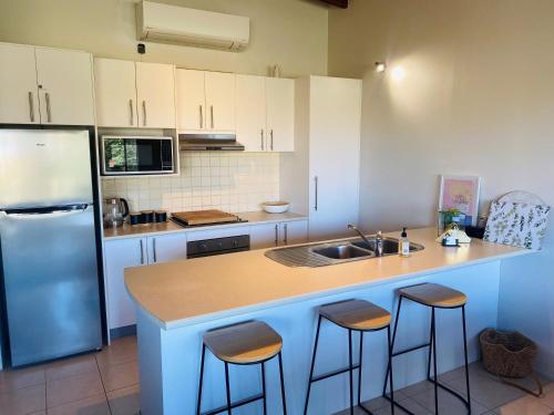 a kitchen with a sink and a counter with bar stools at ELM Accommodation - Merrijig in Merrijig
