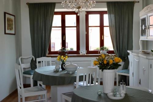 uma sala de jantar com mesa, cadeiras e janelas em Penzion U Kapra em Roudnice nad Labem
