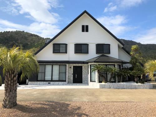 a white house with palm trees in front of it at BIWAKO RESORT Second House in Omihachiman